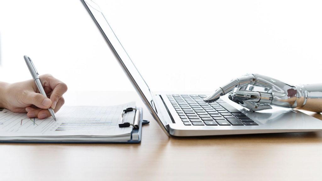 Robot hand using laptop and man hand writing stock photo