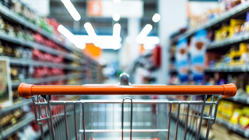 Abstract blurred photo of store with trolley in department store bokeh background. Supermarket aisle with empty red shopping cart (Abstract blurred photo of store with trolley in department store bokeh background. Supermarket aisle with empty red shop