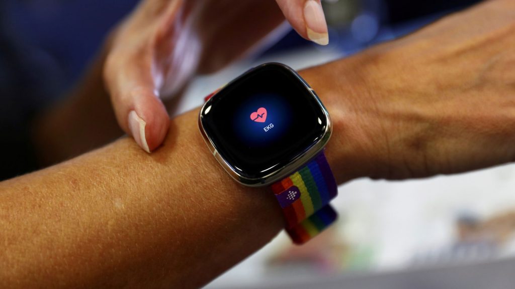 An employee uses an electrocardiogram function on a Fitbit smartwatch at the IFA consumer technology fair, in Berlin