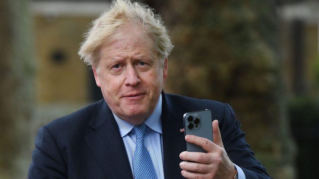 Boris Johnson holds his mobile phone after voting in the local elections in 2022